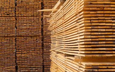 Wooden boards, lumber, industrial wood, timber. Pine wood timber stack of natural rough wooden boards on building site. Industrial timber building materials