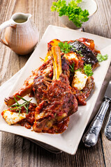 Traditional Greek braised lamb knuckle with feta cheese and eggplant in spicy tomato sauce served as close-up