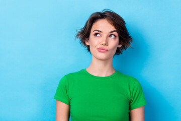 Photo of doubtful unsure woman dressed green top looking empty space isolated blue color background