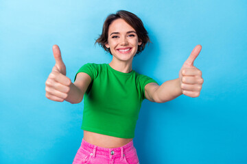 Photo of shiny confident woman wear green t-shirt showing you two thumbs up isolated blue color...
