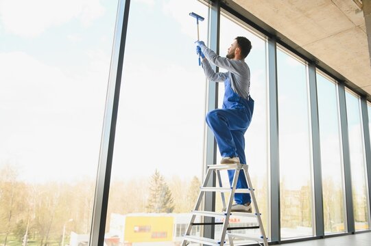 Young Man Cleaning Window In Office