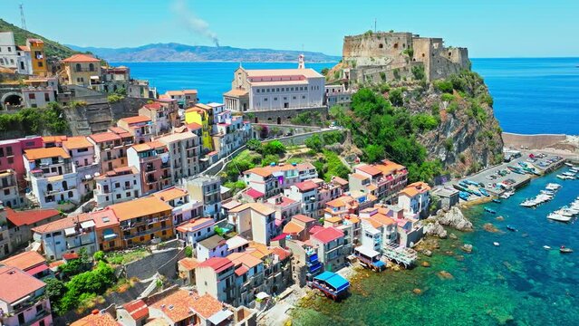 Aerial view of touristic Scilla town with colourful houses in ProRes 4K in Italy. Scenic Italian resort town with crystal clear transparent Mediterranean sea in Europe.