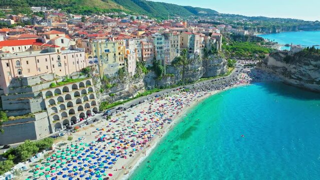 Top view of people relaxing at Shore of Tropea and Spiaggia della Rotonda beach. View from above of tourists having good time on a vacation in the byzantine historical town in ProRez.