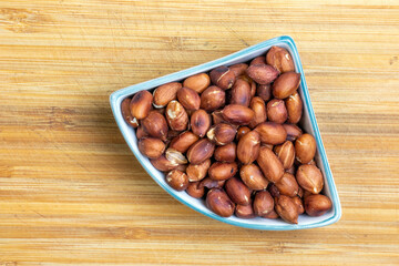 Obraz premium Roasted peanuts in a plate on a wooden kitchen board.