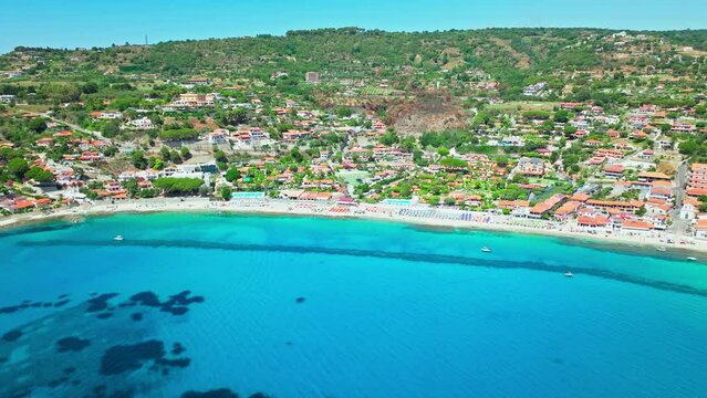 Aerial view of people relaxing at Spiaggia di Grotticelle beach with blue sea. Tourists enjoy a vacation on a summer day at Capo Vaticano, Province of Vibo Valentia, Italy.