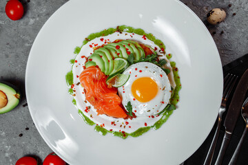 Poached eggs on top of smashed avocado on sourdough toast with smoked salmon. Healthy breakfast with plate on table. Top view. Copy space to right