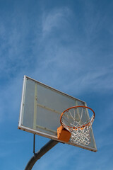 Naklejka premium Outdoor neighborhood basketball court park and recreational area, Basketball net and backboard against sunny blue sky with copy space