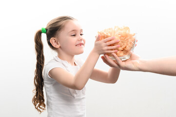 Little girl is given a big bowl of chips snacks with lard, white background portrait of little girl eating chips.