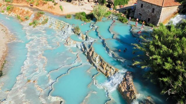 Aerial view of beautiful sunrise over Saturnia thermal baths in Italy. People enjoy Saturnia thermal hot springs of silk blue water pools heated by the nearby volcano in Tuscany.