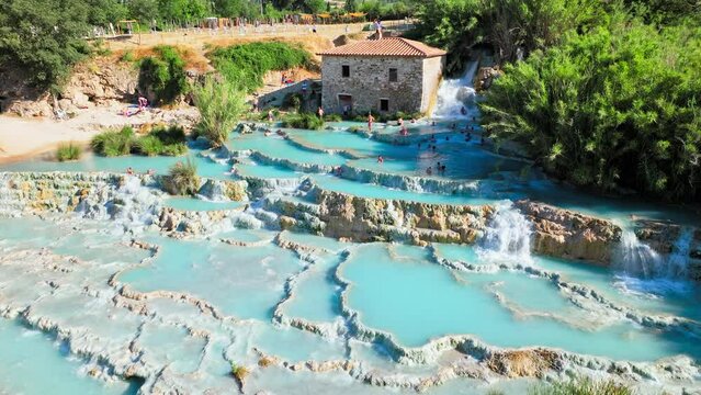 Aerial view of hot springs and thermal waters in Saturnia, Tuscany. View from above of people taking baths and enjoying the spa town in Tuscany in 4K PoRes.