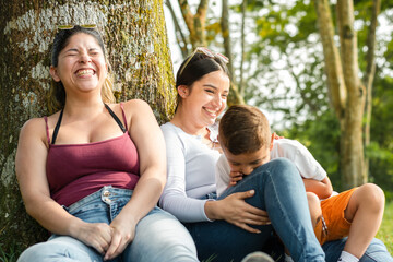 couple of young women, laughing out loud, while talking and spending time with their young son