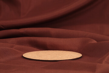 Wooden circle disk platform podium on brown silk fabric background. Minimal empty display product...