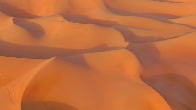 The drone flies to the quadra in cycles standing on sand dunes in the desert of the United Arab Emirates
