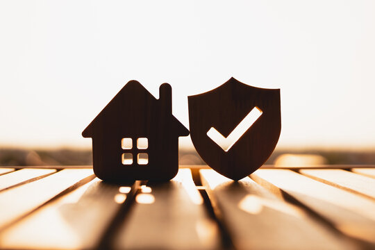 Silhouette of  Wooden house model and real estate insurance ideas, and small shield icon. Housing insurance against impending loss and fire, building fire insurance concepts.