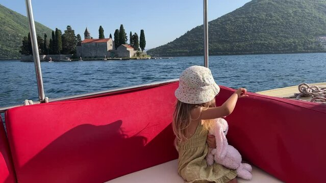 Little girl is sailing in a boat on the Bay of Kotor past the island of St. George