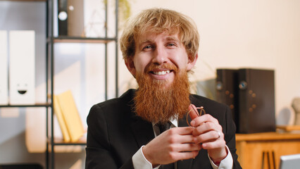 Confident happy young bearded businessman in glasses looking at camera with smile at home office...