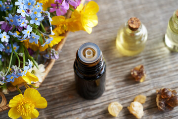 Essential oil bottle with frankincense resin and spring flowers