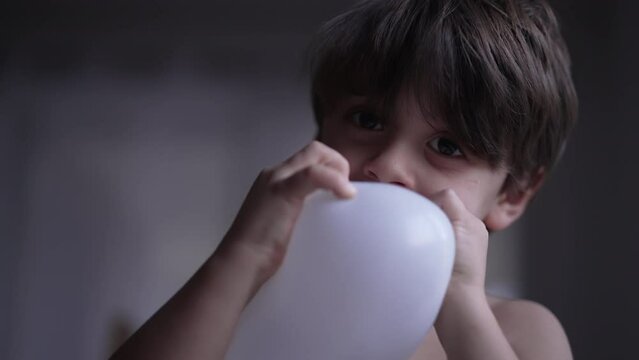 One Cute Little Boy Blowing Up Balloon With Mouth. Child Biting Balloon With Teeth