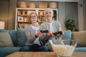 Two senior women caucasian friends or sisters play console video game
