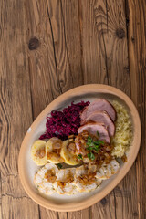 smoked meat served with red and white cabbage and two kinds of dumplings