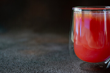 Glass with red watermelon juice on dark background