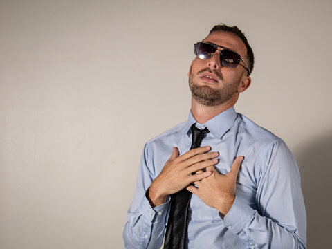 Hombre elegante llevando sus manos al pecho en gesto de dolor y pesar
