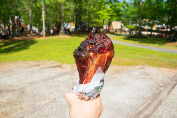 A massive grilled or barbecued turkey leg. The drumstick is marinated and wrapped in aluminum foil....