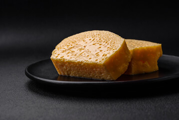Delicious porous yellow cheese cut in large pieces on a ceramic plate