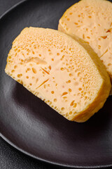 Delicious porous yellow cheese cut in large pieces on a ceramic plate