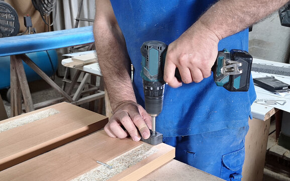 Hands of carpenter uses hand drill to assemble the wood