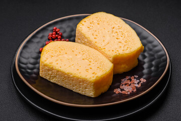 Delicious porous yellow cheese cut in large pieces on a ceramic plate