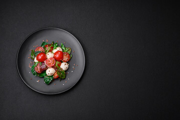 Delicious fresh salad with mozzarella cheese, cherry tomatoes, herbs, salt and spices