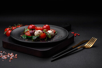 Delicious fresh salad with mozzarella cheese, cherry tomatoes, herbs, salt and spices