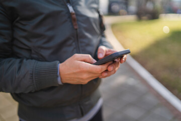 A man using and talking on his phone outside in park during the day