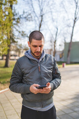 A man using and talking on his phone outside in park during the day