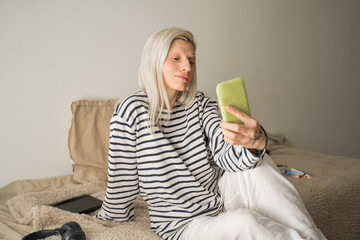 Smiling young woman at home using modern smartphone