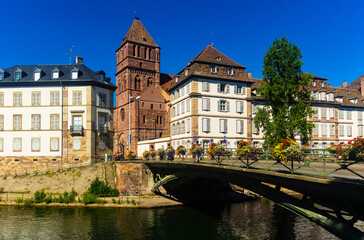 Fototapeta na wymiar Scenic view of Strasbourg cityscape on sunny summer day overlooking historical building of St Thomas Church on bank of Ill river
