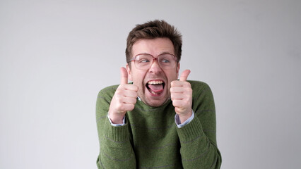European young man shows a thumbs up. He is thrilled with the result