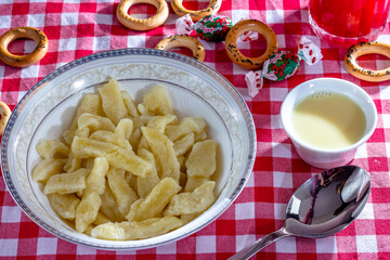 Russian and Ukrainian cuisine. Lazy dumplings with sugar, butter and sour cream in a white plate with a spoon on a light grey background. Flatlay, top view. Background image, copy space