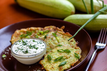 Baked vegetable pancakes with pumpkin and zucchini, served with sour cream dip