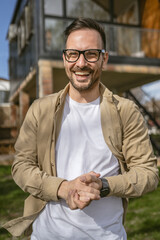 One adult man stand outdoor in front of his house happy confident