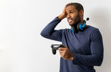 A dark-skinned man who grabs joystick hands to play video games and wears a headset with a...