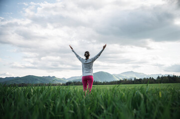 Low angle rear view of a woman standing in the middle of green field