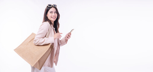 Cheerful shopper woman carry eco tote handbag holding mobile phone looking copy space standing on...