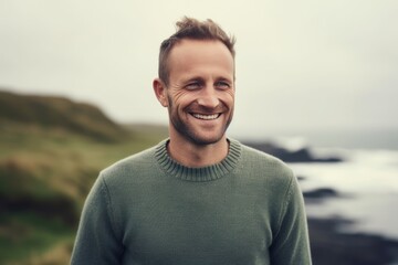 Medium shot portrait photography of a pleased man in his 30s wearing a cozy sweater against a summer landscape or beach background. Generative AI