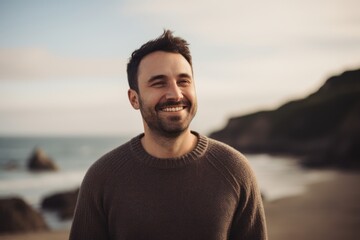 Portrait of a handsome young man smiling on the beach at sunset