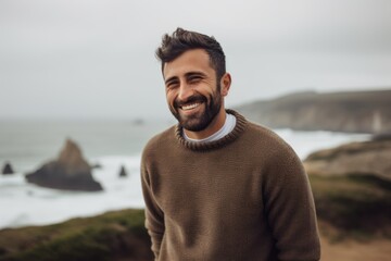 Portrait of a handsome young man in sweater standing on the beach