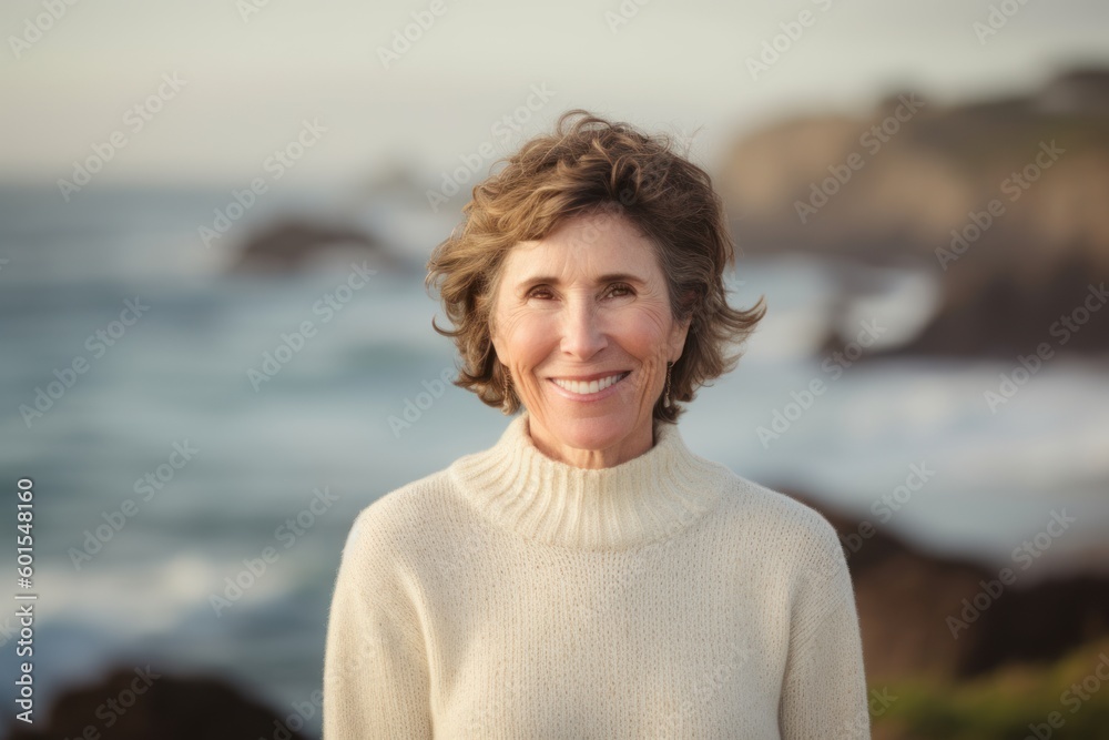 Wall mural Portrait of smiling senior woman standing on beach at the day time