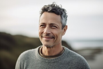 Portrait of a handsome middle-aged man in a gray sweater on the beach