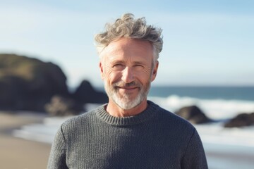 Fototapeta premium Portrait of smiling man with grey hair at the beach on a sunny day